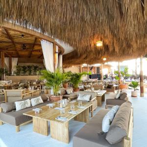 邦涛海滩Arinara Beach Resort Phuket - SHA Extra Plus的餐厅设有长沙发和桌子,拥有稻草屋顶