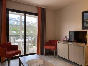 佩罗斯-吉雷克Appartement Perros-Guirec, 2 pièces, 4 personnes - FR-1-368-403的一间带电视和椅子的客厅以及一个阳台