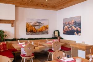 圣莫里茨Hotel Corvatsch的餐厅设有桌椅,墙上挂有绘画作品