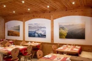 圣莫里茨Hotel Corvatsch的餐厅设有桌椅,墙上挂有绘画作品