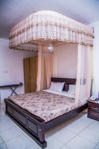 恩德培Hidden Treasure Serviced Hotel Apartments HITSHA HOTELS Entebbe的卧室内一张带天蓬的床