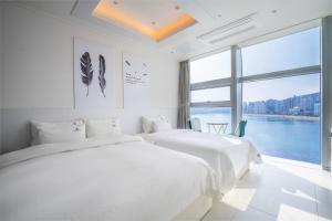釜山Oceanstay Hotel的白色客房的两张床,设有大窗户