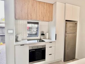 基督城Urban Locale: Bars, eats & shops的厨房配有白色橱柜和不锈钢冰箱