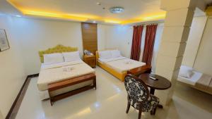 达沃市安克拉酒店的一间卧室配有两张床、一张桌子和一把椅子