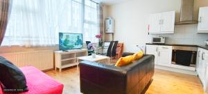 伦敦Lilac at Hammersmith的客厅配有沙发和带电视的桌子