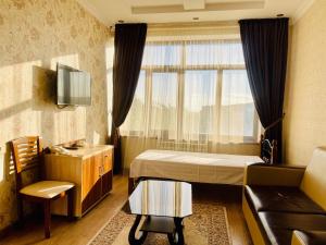 奎兹洛达Dostyk的一间卧室配有一张床、一张沙发和一个窗口