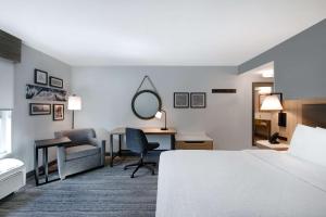 安德森安德森/联盟商务园区汉普顿酒店的酒店客房带一张床、一张书桌和一面镜子