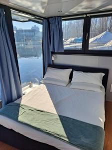 多尔梅莱托Floating Experience Black Pearl, Lago Maggiore的船后方的一张床铺,设有两个窗户
