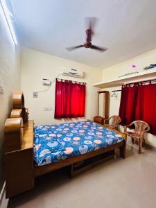 PerambalūrSirvachur madhurakalli amman guest house的一间卧室配有床和红色窗帘