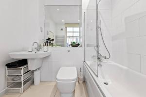 伦敦Luxurious 3 Bedroom Flat in Haymarket London Sleeps 14 HY1的白色的浴室设有卫生间、水槽和浴缸。
