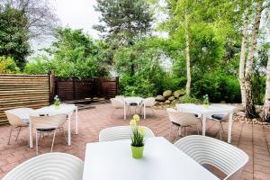 埃朗根厄尔兰根精选酒店的庭院配有白色的桌椅和树木