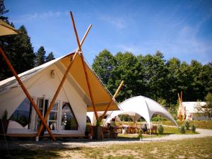 Bughea de JosPINIALE GLAMPING TRIB的大型白色帐篷,配有木杆