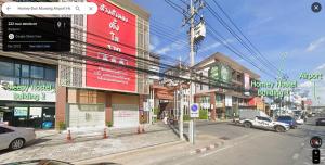 曼谷Sleepy and Homey Don Mueang Airport Hostel的一条城市街道,汽车停在建筑前