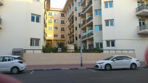 迪拜Ruby Star Hostel Loft Bed 21的两辆白色汽车停在大楼旁边的停车场
