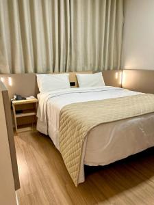 因达亚图巴阿尔吉酒店的卧室配有一张白色大床和一张边桌
