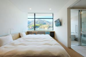尾道市BONAPOOL的一间卧室设有一张大床和大窗户