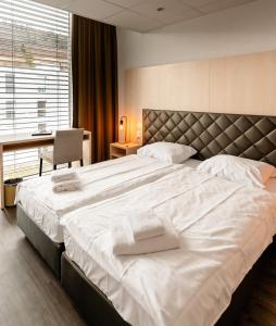 贝尔普Los Lorentes Aparthotel Bern Airport的一间卧室配有一张大床,上面有白色毛巾