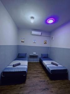 拿笃Doyar's Home Stay (Palm Garden -1st Floor)的一间设有两张床和紫色光的房间
