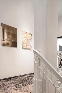 布达佩斯Hotel GIN Budapest的墙上有两幅画作的白色楼梯