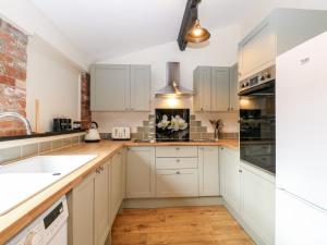 北沃尔舍姆Squirrel Lodge的厨房铺有木地板,配有白色橱柜。