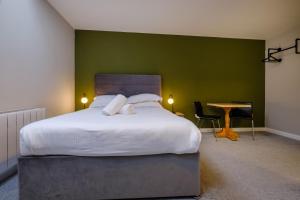 温德米尔Station Lodge - FREE off-site Health Club access with Pool, Sauna, Steam Room & Gym的一间卧室设有一张大床和绿色的墙壁