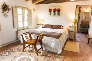 克鲁尔雷斯Mas Gran de Cruïlles - Mas Rural - Hotel & Events的一间卧室配有一张床和一把椅子