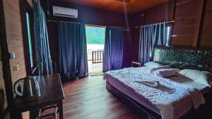 RabiaThe Jeti Mangrove - Ecolodge, Cottage, Restaurant & Kali Biru, Blue River的一间卧室配有一张床、一张桌子和一个窗户。