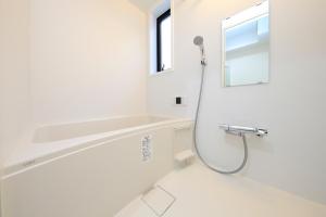 东京COTO Tokyo Sugamo的带淋浴和镜子的白色浴室