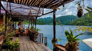 RabiaThe Jeti Mangrove - Ecolodge, Cottage, Restaurant & Kali Biru, Blue River的水面上配有桌椅的码头