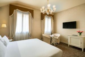 威尼斯Residenza Venezia | UNA Esperienze的酒店客房配有一张床、一张书桌和一个吊灯。