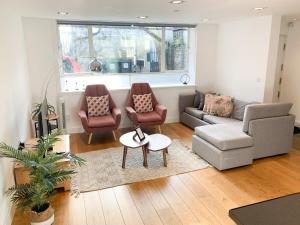 伦敦Bright, spacious, 3-bedroom Emirates apartment with terrace的客厅配有沙发、椅子和桌子