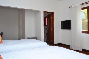 马普托Kutenga Guest House的一间卧室配有两张白色的床和电视
