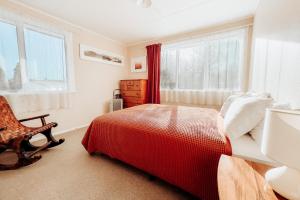 图朗伊Alpine House Tongariro - Turangi Holiday Home的一间卧室配有一张床、一把椅子和窗户。