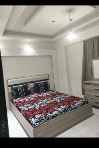 艾因苏赫纳porto sokhna Pyramids Apartment Familis的一间卧室配有一张带红色和黑色毯子的床