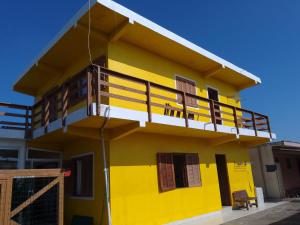 因贝Pousada do Osvaldo Imbé的黄色房子的顶部设有阳台