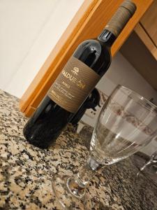 贝纳尔马德纳Arenal golf Sun & golf的葡萄酒杯旁的一瓶葡萄酒