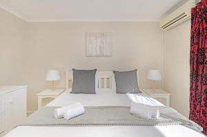 布鲁堡史特兰Ocean Tides 35的白色卧室配有一张带两个枕头的大床