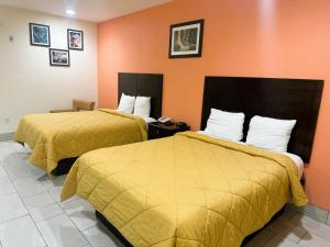 圣安东尼奥Pecan Valley Inn & Suites的橙色墙壁的酒店客房内的两张床