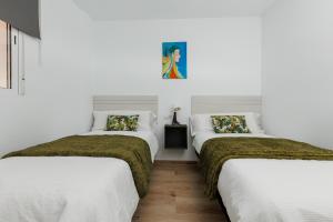 马拉加Casa Carmen的白色墙壁的客房内的三张床