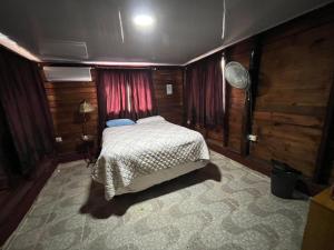 圣地亚哥洛斯卡巴萨纳萨尔瓦多亚尔丁赛克勒托旅舍的卧室配有一张床铺,位于带木墙的房间内