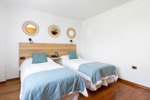 拉拉古纳Casa Lali Habitación 2的配有白色墙壁和木地板的客房内的两张床