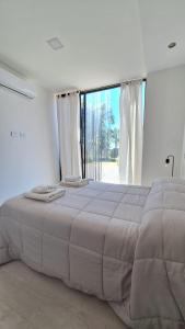 罗卡将军市Cubil Naranja. Casa conteiner 2 dormitorios的白色的客房设有一张大床和大窗户