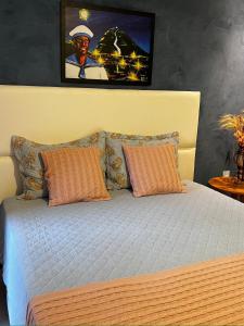 雅科比纳Hotel Villa Babaçu的一张带橙色枕头的床和墙上的照片