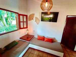皮帕Chalé Centro, Praia Pipa的客房设有带红色枕头的沙发和窗户。