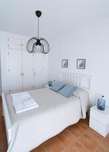 阿亚蒙特Apartamento Atardeceres的卧室配有白色的床和吊灯。