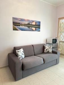 维纳利亚瑞勒Ca' Mariuccia appartamento in Venaria Reale的客厅的沙发,墙上有绘画作品