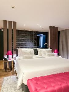 戈亚尼亚QS Marista Hotel的大卧室设有一张大床和红色长凳