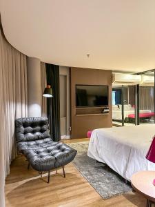戈亚尼亚QS Marista Hotel的配有一张床和一把椅子的酒店客房