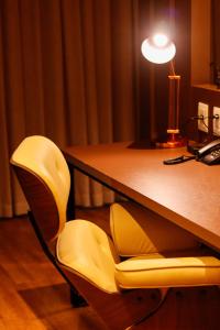 戈亚尼亚QS Marista Hotel的一张带黄椅的桌子和一张带台灯的桌子