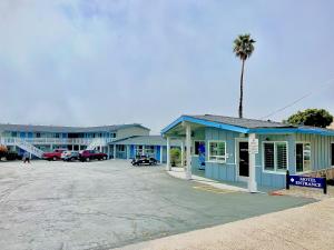 皮斯莫比奇大洋棕榈汽车旅馆的停车场内种植棕榈树的蓝色建筑